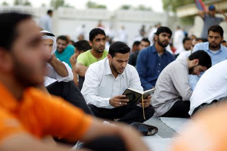 A supporter reads Holly Quran as he participates in a sit-in outside the home of Bahrain's leading Shi'ite cleric Isa Qassim in the village of Diraz west of Manama, Bahrain June 21, 2016. REUTERS/Hamad I Mohammed