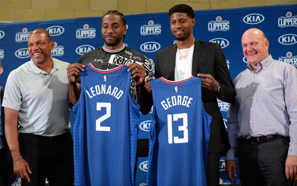 Los Angeles Clippers players Paul George and Kawhi Leonard pose for photographs with head coach Doc Rivers and owner Steve Ballmer in 2019.