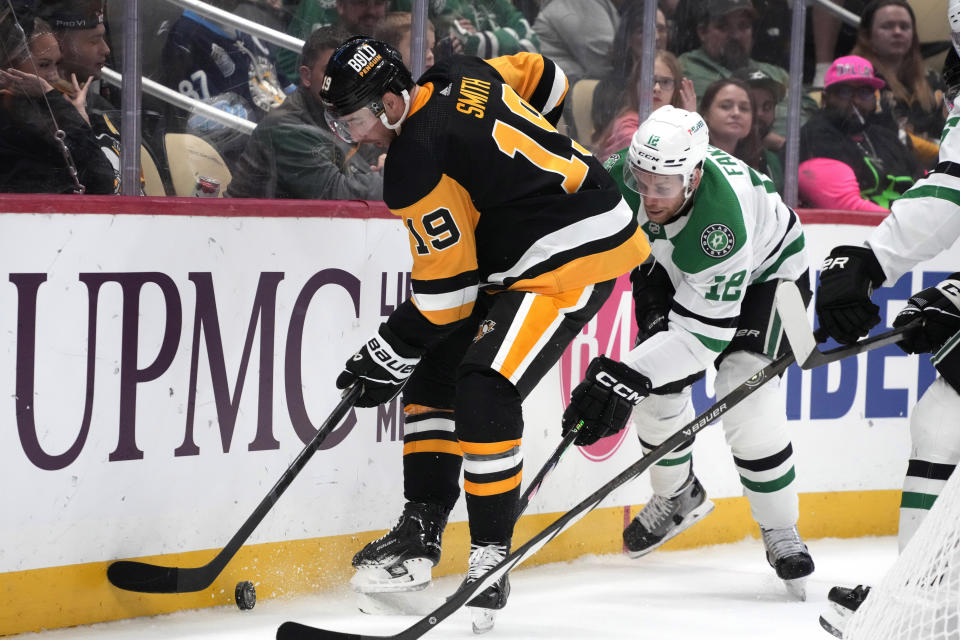 Pittsburgh Penguins' Reilly Smith (19) works the puck behind the net with Dallas Stars' Radek Faksa (12) defending during the second period of an NHL hockey game in Pittsburgh, Tuesday, Oct. 24, 2023. (AP Photo/Gene J. Puskar)