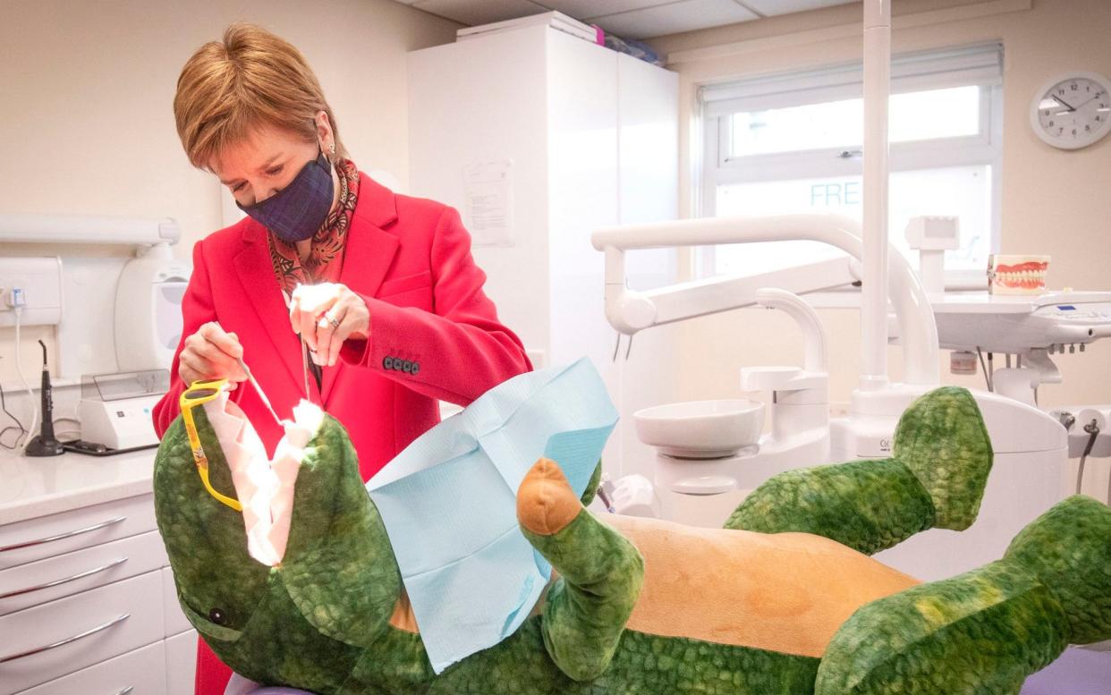 Scotland's First Minister Nicola Sturgeon, leader of the Scottish National Party, checks the teeth of 'Dentosaurus' during a visit to the Thornliebank Dental Care centre in Glasgow during the election campaign. Scotland holds its next parliamentary election on May 6 this year - Jane Barlow/PA Wire