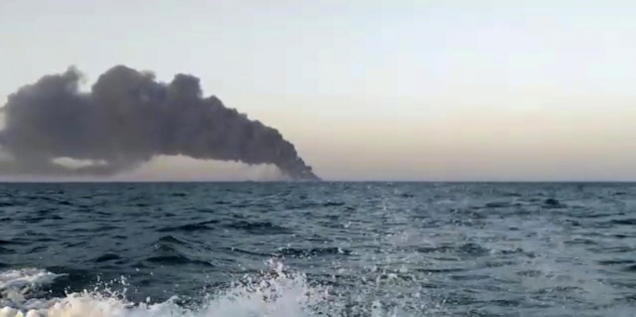 This image made from a video released on Wednesday, June 2, 2021 by Asriran.com, shows smoke rising from Iran's navy support ship Kharg in the Gulf of Oman. Kharg, the largest warship in the Iranian navy caught fire and later sank Wednesday in the Gulf of Oman under unclear circumstances, semiofficial news agencies reported. (Asriran.com via AP)