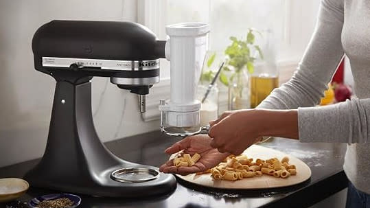  Woman making pasta with a KitchenAid pasta machine. 