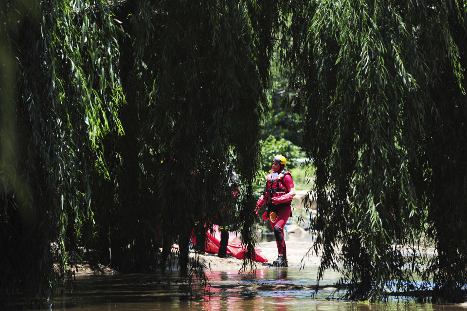 A rescue worker stands next to a body retrieved from the Jukskei river in Johannesburg, Sunday, Dec. 4, 2022. At least nine people have died while eight others are still missing in South Africa after they were swept away by a flash flood along the Jukskei river in Johannesburg, rescue officials said Sunday. (AP Photo)