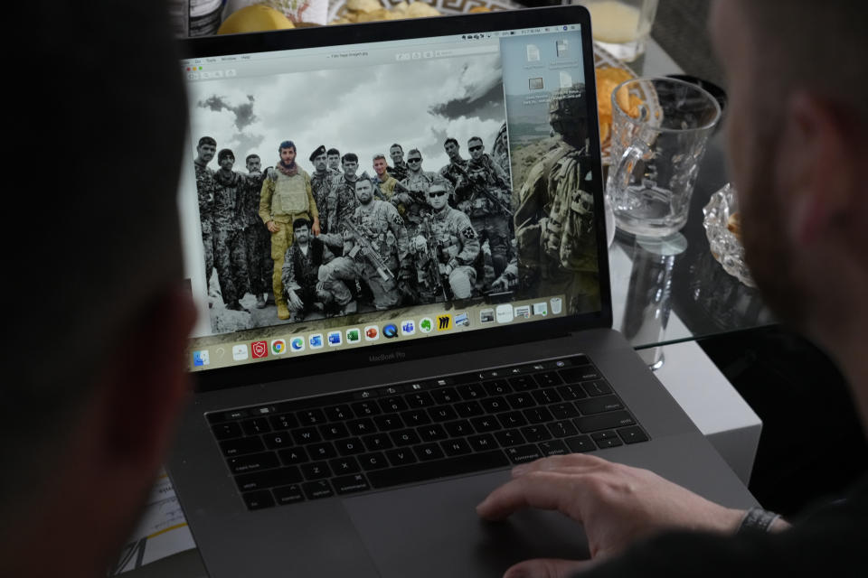 U.S. Army veteran Spencer Sullivan, right, and seen on the computer screen in color at right, and Abdulhaq Sodais, who served as a translator in Afghanistan, left, and seen on the computer screen in color on the left, talk at Sodais' apartment in Bremen, Germany, Friday, Aug. 13, 2021, while looking at images taken in Afghanistan. (AP Photo/Peter Dejong)