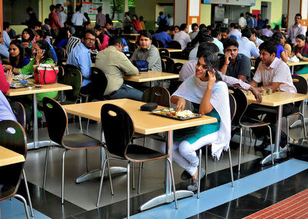 An employee speaks on a mobile phone as she eats her lunch at the cafeteria in the Infosys campus in Bengaluru, India, September 23, 2014. REUTERS/Abhishek N. Chinnappa/File Photo