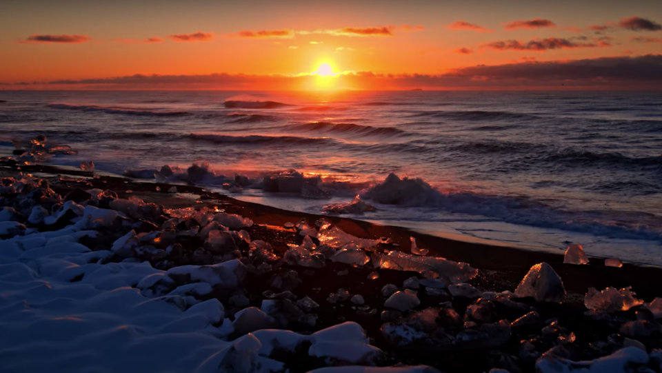 A sunset overlooks a rocky shore.