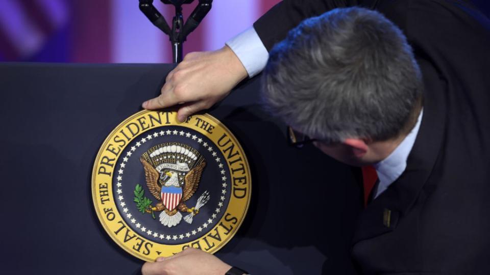  An aide places the presidential seal on Joe Biden's lectern. 