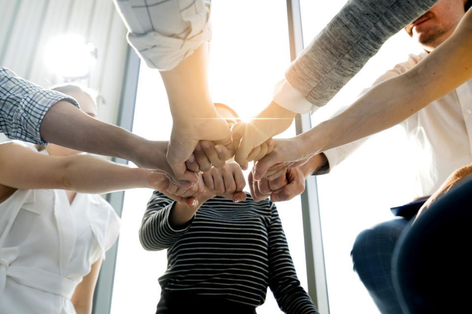 people putting their hands in the center of a circle in an office