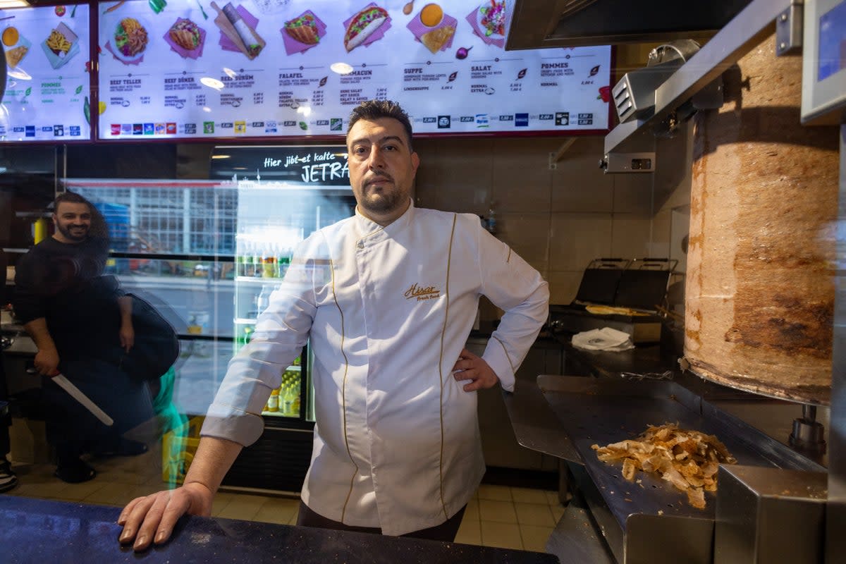 Arif Keles, a third-generation barbecue snack bar owner poses next to the doner kebab meat skewer in Berlin  (AFP via Getty Images)