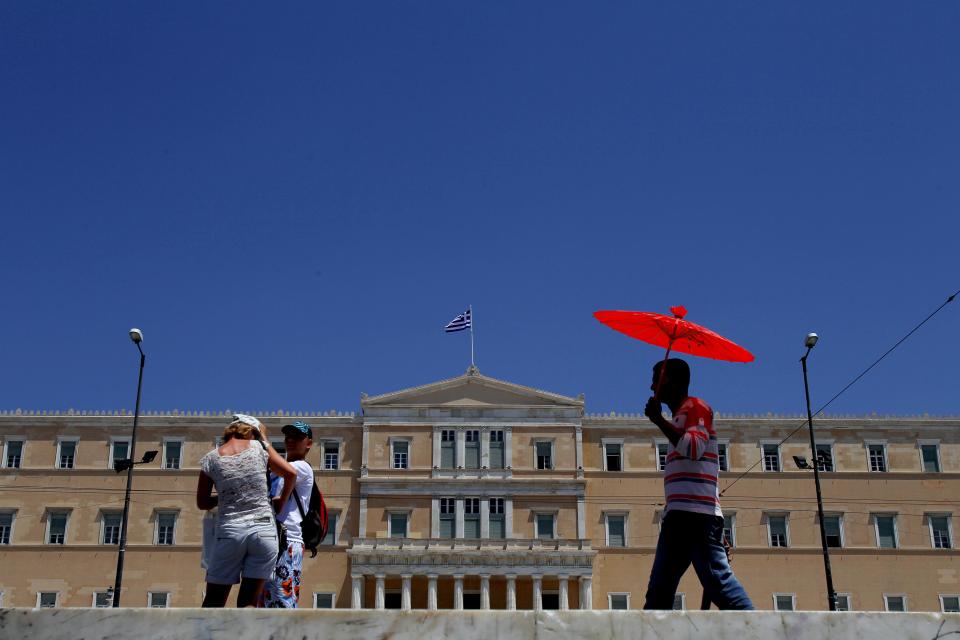 A couple of tourist, left, stand in front of a Greek parliament as another person, right, sells umbrellas at Syntagma square in Athens, Tuesday, June 12, 2012. Greece faces crucial national elections on Sunday, that could ultimately determine whether the debt-saddled, recession bound country remains in the eurozone. First elections on May 6 resulted in a hung parliament. (AP Photo/Petros Karadjias)