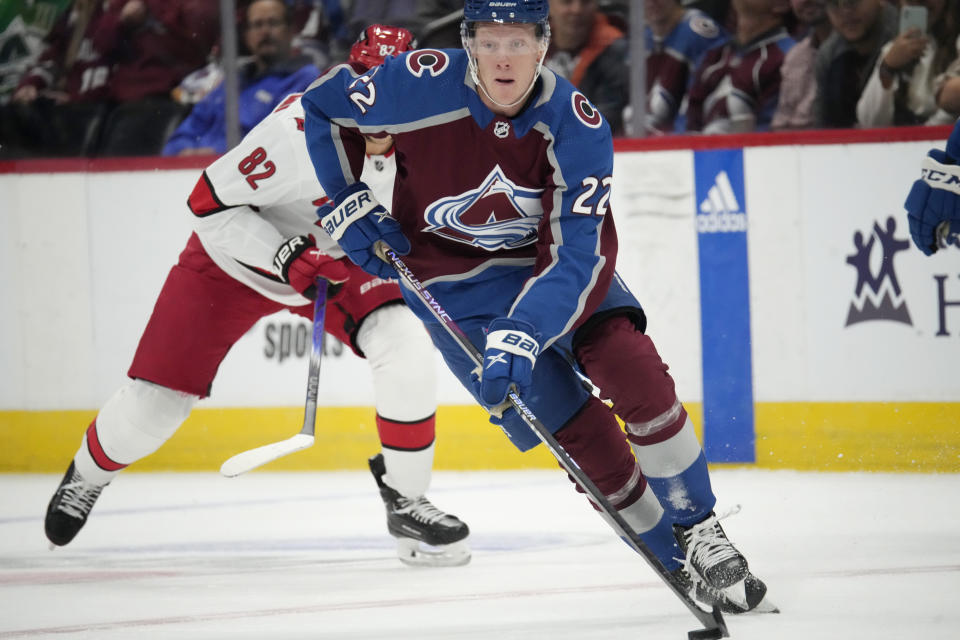 Colorado Avalanche center Fredrik Olofsson (22) picks up the puck as Carolina Hurricanes center Jesperi Kotkaniemi (82) pursues in the first period of an NHL hockey game Saturday, Oct. 21, 2023, in Denver. (AP Photo/David Zalubowski)