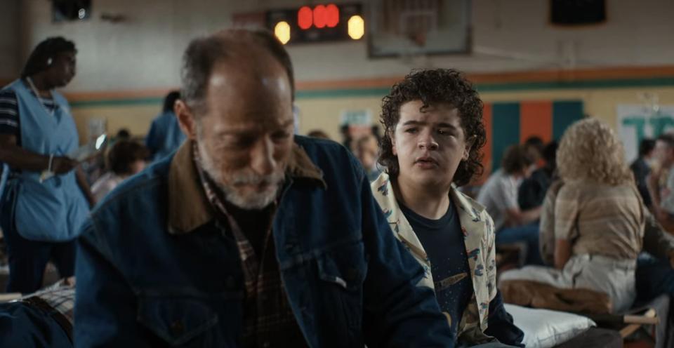 Dustin with Eddie's uncle in a crowded gymnasium in "Stranger Things"