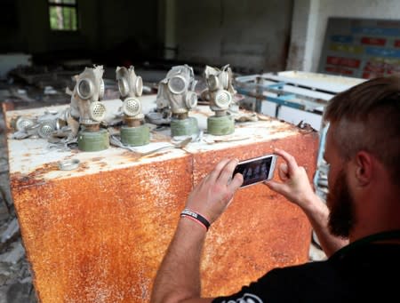 A visitor takes a picture of gas masks at a former base of the Soviet army, near the Chernobyl Nuclear Power Plant