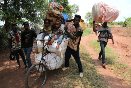 Congolese migrants expelled from Angola push a rented bicycle to transport their children and belongings along the road to Tshikapa, Kasai province near the border with Angola, in the Democratic Republic of the Congo, October 12, 2018. REUTERS/Giulia Paravicini