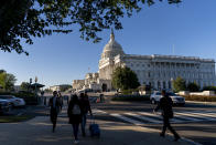 People walk by the U.S. Capitol in Washington, Tuesday, Oct. 19, 2021. A centerpiece of President Joe Biden's climate change strategy all but dashed, lawmakers are heading Tuesday to the White House as Democrats search for for common ground on ways to narrow and reshape his sweeping $3.5 trillion budget plan. (AP Photo/Andrew Harnik)