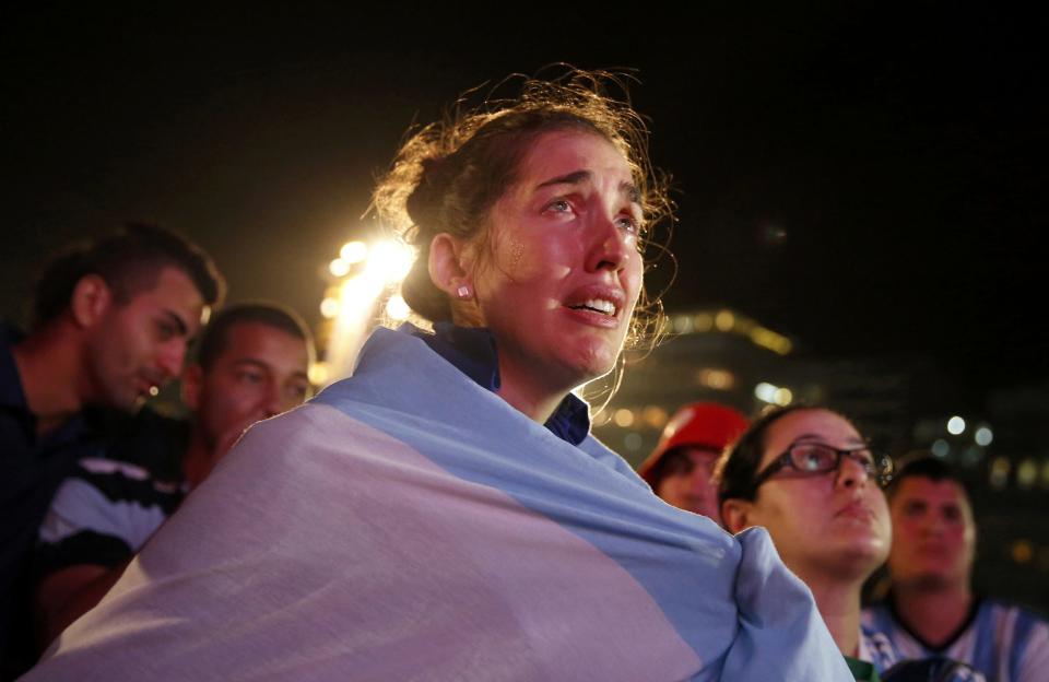 An Argentine fan cries as she watches Argentina's defeat to Germany in their 2014 World Cup final match, on Copacabana beach in Rio de Janeiro July 13, 2014. REUTERS/Pilar Olivares (BRAZIL - Tags: SOCCER SPORT WORLD CUP TPX IMAGES OF THE DAY)