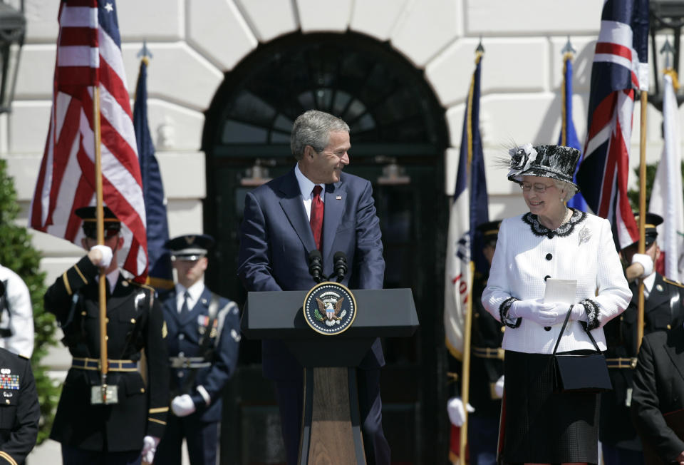 President George W. Bush, at a podium with the presidential seal, and Queen Elizabeth II by his side, flanked by flags and Marines.