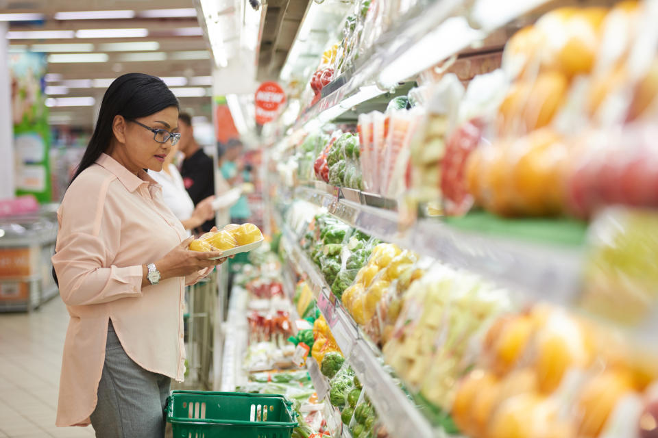 A woman standing in the produce aisle of a grocery store.