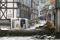 A vehicle and a tree lie down following a heavy rain in Hita, Oita prefecture, southern Japan Wednesday, July 8, 2020. Floodwaters flowed down streets in southern Japanese towns hit by heavy rains. (Kyodo News via AP)