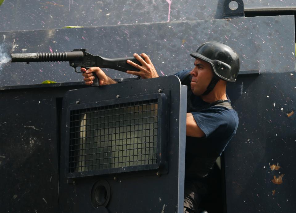 A Bolivarian National Police fires tear gas at anti-government protesters during clashes in Caracas, Venezuela, Tuesday, April 1, 2014. Protesters had gathered to march to the National Assembly with opposition lawmaker Maria Corina Machado, who was stripped of her parliamentary seat last week, after addressing the Organization of American States about the conditions of Venezuela. Riot police prevented the protesters from reaching the assembly. (AP Photo/Fernando Llano)