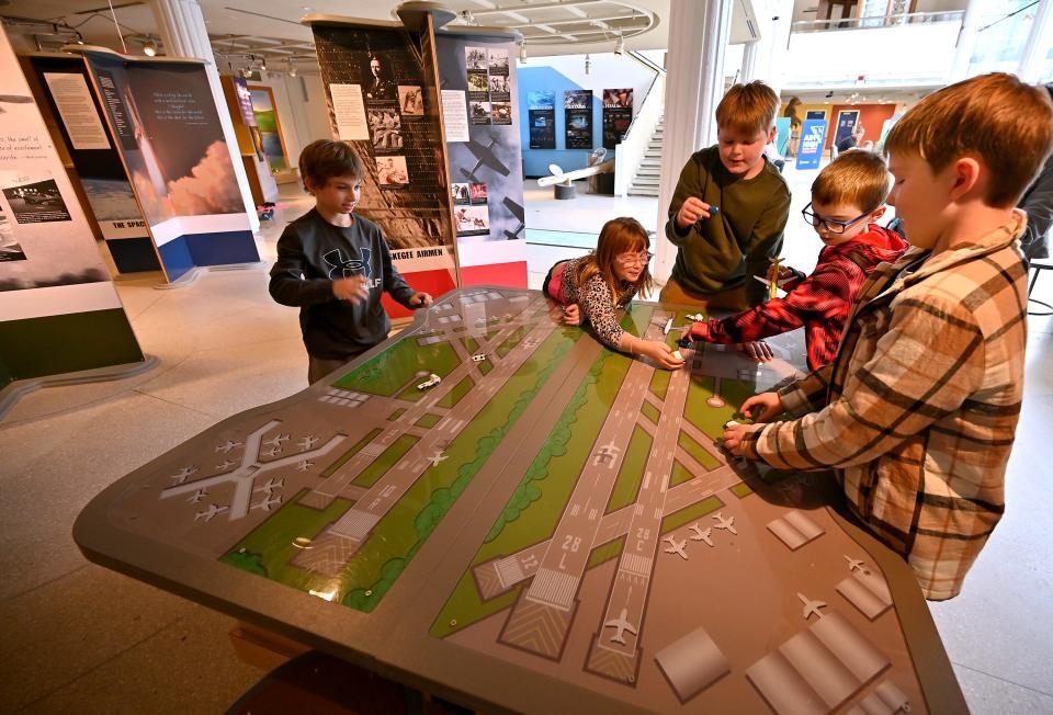 Children play with a runway table that is part of the exhibit "Aim High: Soaring with the Tuskegee Airmen."