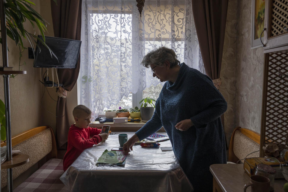 Iryna Kopan, plays with her 6-year-old grandson Nazar, at an apartment given to them by a family member after fleeing their home in Kyiv, in Lviv, western Ukraine, Sunday, April 3, 2022. For years, Iryna, an architect, has poured her money and talent into building her daughter's new home. "The job of my life," Iryna says. Her work, like almost everything else, was left behind. (AP Photo/Nariman El-Mofty)