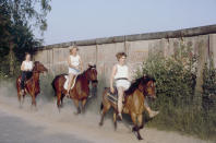 <p>Un grupo de personas monta a caballo junto al muro. (Photo by Thierlein/ullstein bild via Getty Images)</p> 