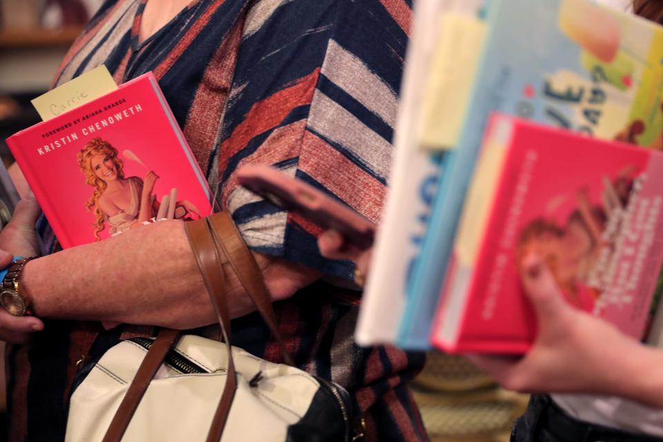 People hold copies of Kristin Chenoweth's new book Monday as they wait in line to get it signed at Full Circle Bookstore in Oklahoma City.