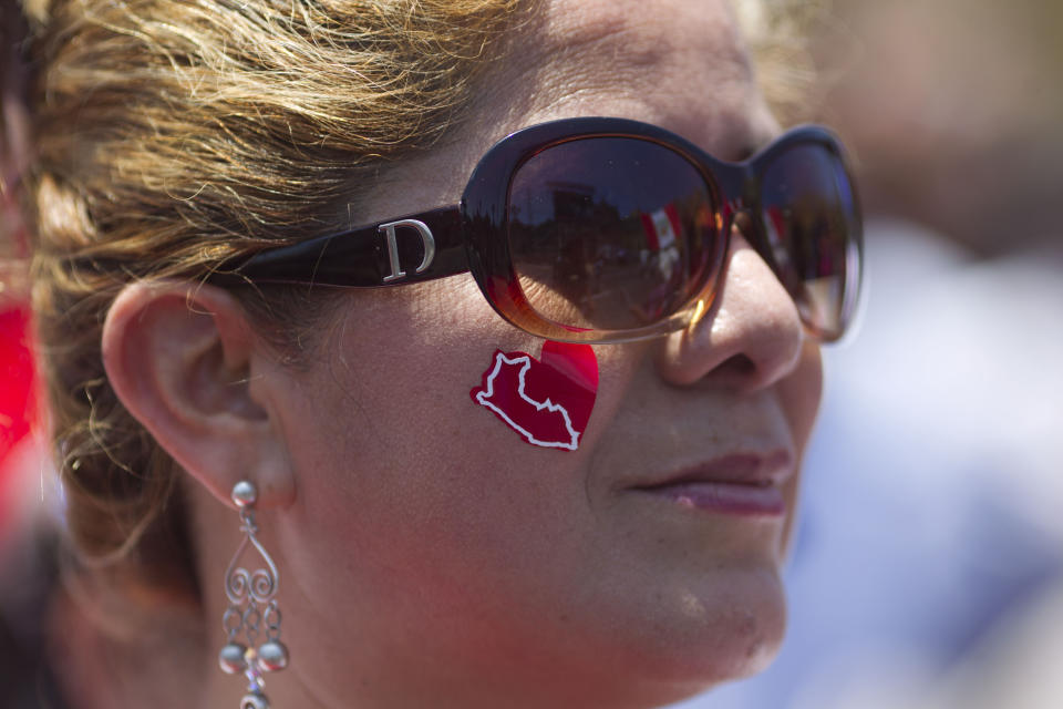 A woman, donning a heart-shaped sticker with a map of Peru on her cheek, attends a ceremony in front of government palace celebrating the World Court decision on the Peru-Chile maritime border, in Lima, Peru, Monday, Jan. 27, 2014. The United Nations' highest court set a maritime boundary between Chile and Peru on Monday, granting the latter a bigger piece of the Pacific Ocean but keeping rich coastal fishing grounds in Chilean hands. (AP Photo/Martin Mejia)