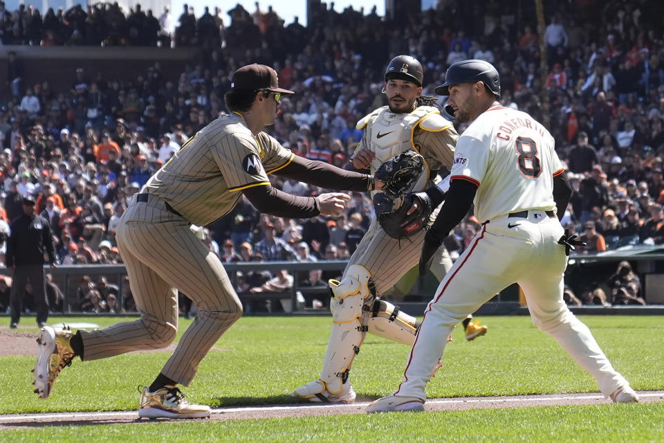 San Diego Padres third base Graham Pauley, left, tags out San Francisco Giants' Michael Conforto (8) in front of catcher Luis Campusano during the fourth inning of a baseball game in San Francisco, Friday, April 5, 2024. (AP Photo/Jeff Chiu)