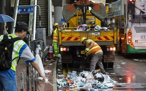 Workers clear trash outside the Legislative Council building a day after violent clashes over a proposed extradition bill in Hong Kong, China - Credit: Justin Chin/Bloomberg