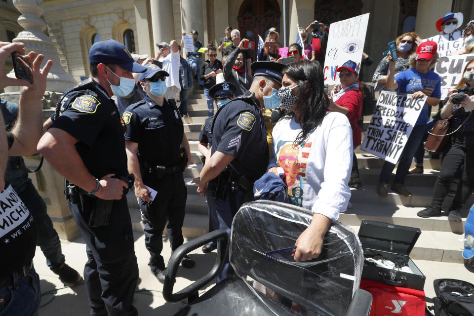 A Michigan State Police trooper talks with hair stylist Jody Hebberd while giving free haircuts at the State Capitol during a rally in Lansing, Mich., Wednesday, May 20, 2020. Barbers and hair stylists are protesting the state's stay-at-home orders, a defiant demonstration that reflects how salons have become a symbol for small businesses that are eager to reopen two months after the COVID-19 pandemic began. (AP Photo/Paul Sancya)