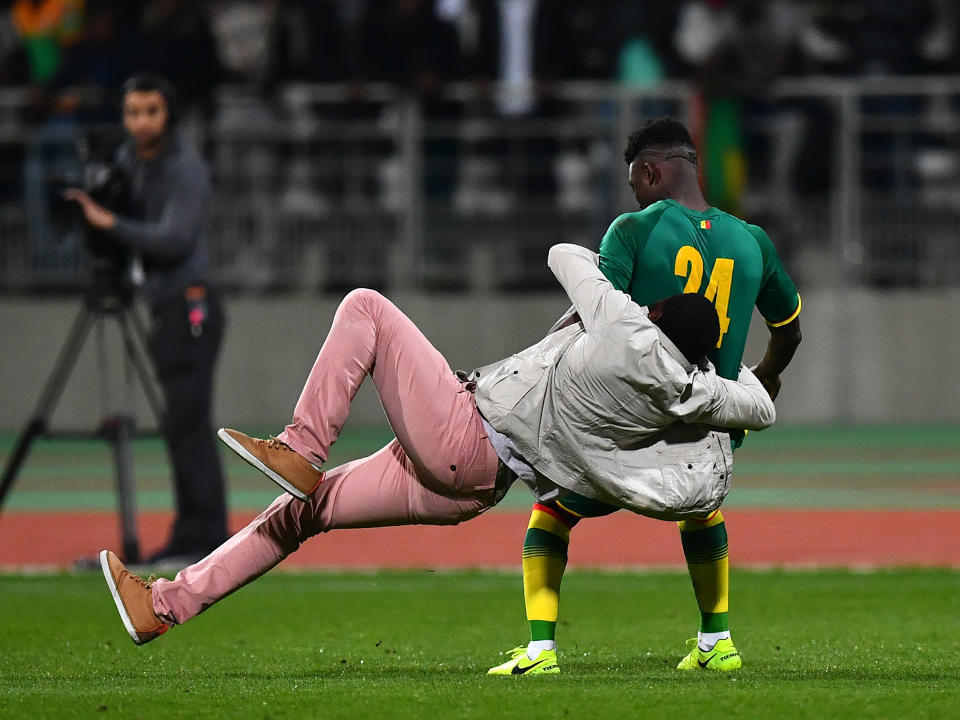 A pitch invader tackles Lamine Gassama of Senegal: Getty