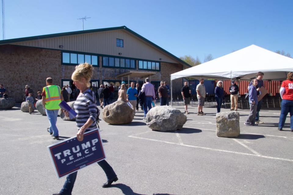 <div class="inline-image__caption"><p>A woman carries a Trump campaign sign following indoor services held at Calvary Chapel May 24 in Orrington, Maine. The signs and other campaign literature were available in the parking lot of the church before and after services May 24, which were held in defiance of state mandates.</p></div> <div class="inline-image__credit">Johanna S. Billings</div>