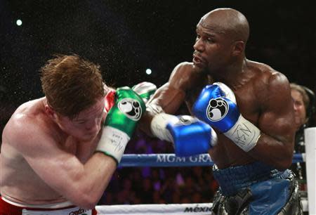 WBC/WBA 154-pound champion Canelo Alvarez (L) takes a punch from Floyd Mayweather Jr. of the U.S. at the MGM Grand Garden Arena in Las Vegas, Nevada, September 14, 2013. REUTERS/Steve Marcus