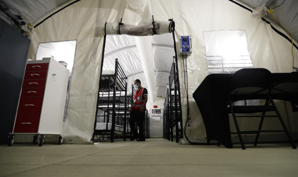 FILE - In this July 9, 2019, file photo, a staff member works in the infirmary, a series of tents, at the U.S. government's newest holding center for migrant children in Carrizo Springs, Texas. The Trump administration will make a case in court to end a longstanding settlement governing detention conditions for immigrant children, including how long they can be held by the government. A hearing is scheduled before a federal judge Friday, Sept. 27, in Los Angeles over the so-called Flores settlement. (AP Photo/Eric Gay, File)