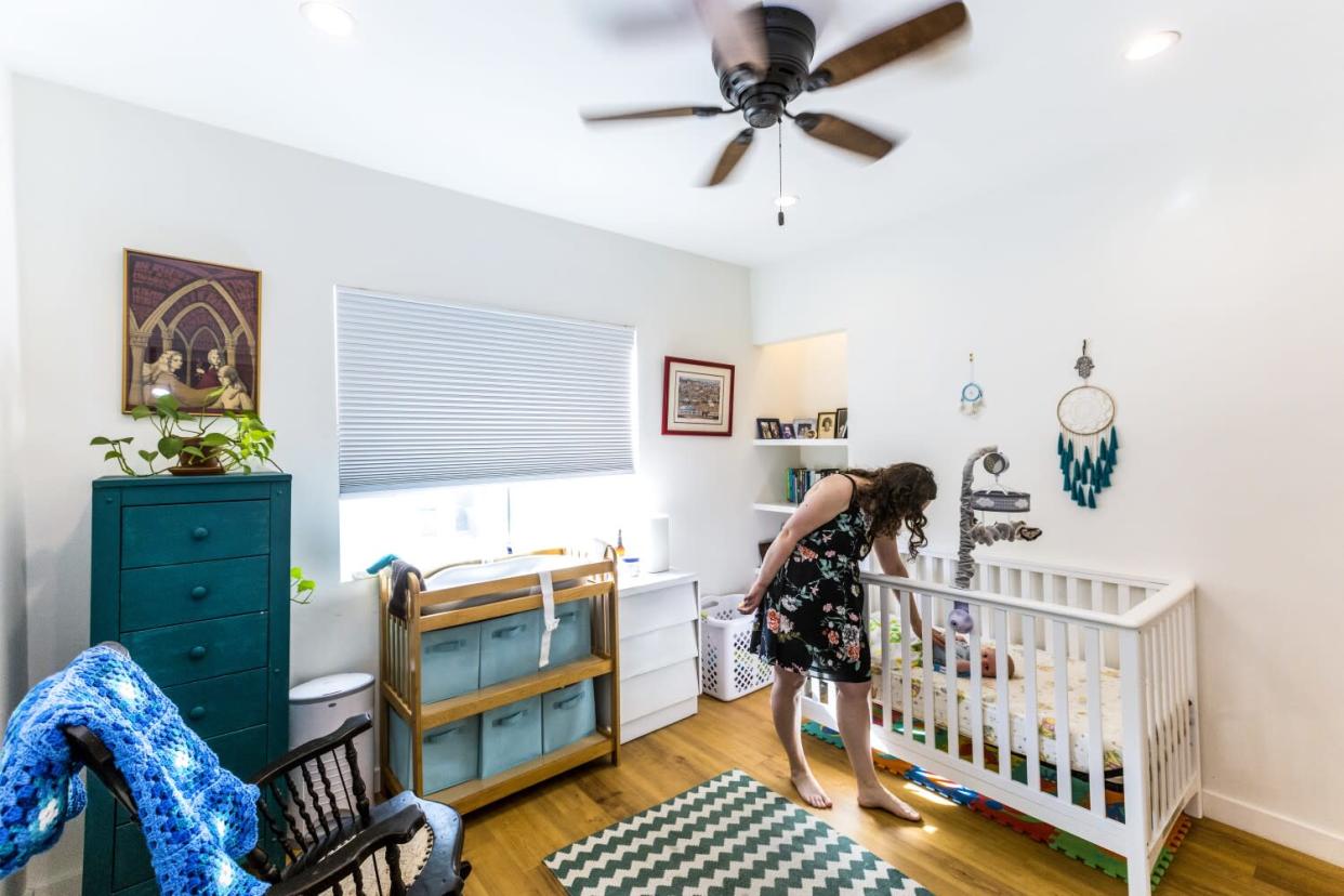 A woman checks on her baby in his crib