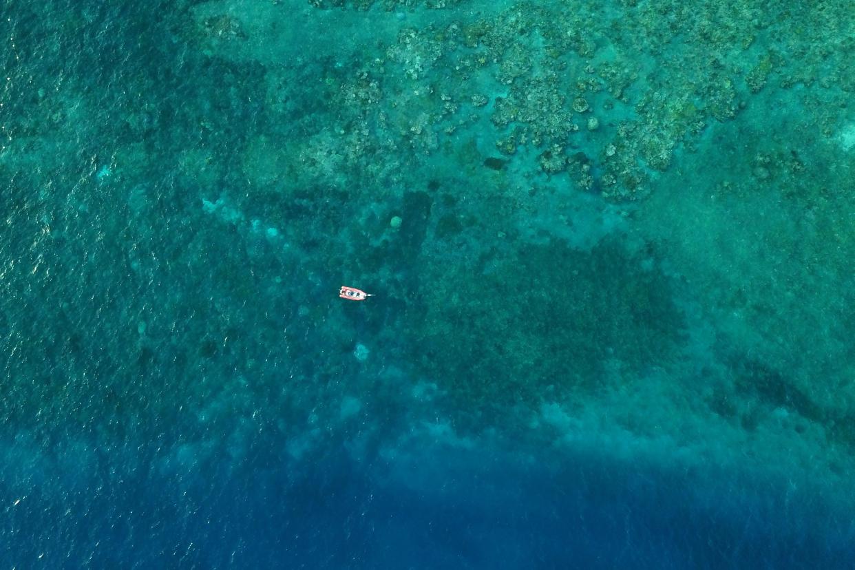 Marine biologists pilot a small boat on the Great Barrier Reef above Moore Reef in Gunggandji Sea Country off coast of Queensland in eastern Australia on Nov. 14, 2022.