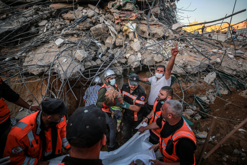 Palestinian workers take part in rescue efforts to pull out a body of a child from rubble.