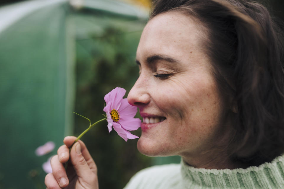 Woman smelling pink flower and smiling