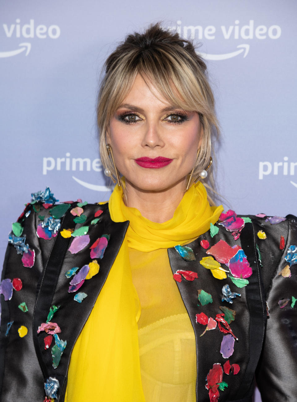 Heidi at an event wearing a sheer top with a satin jacket with appliqués