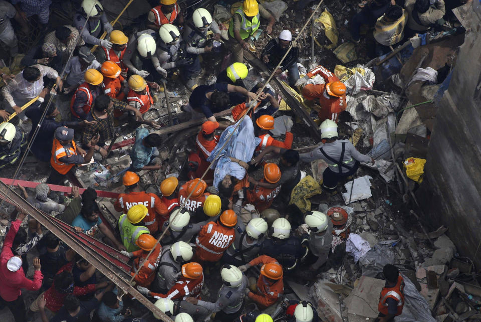 Rescuers carry out a survivor from the site of a building that collapsed in Mumbai, India, Tuesday, July 16, 2019. A four-story residential building collapsed Tuesday in a crowded neighborhood in Mumbai, India's financial and entertainment capital, and several people were feared trapped in the rubble, an official said. (AP Photo/Rajanish Kakade)