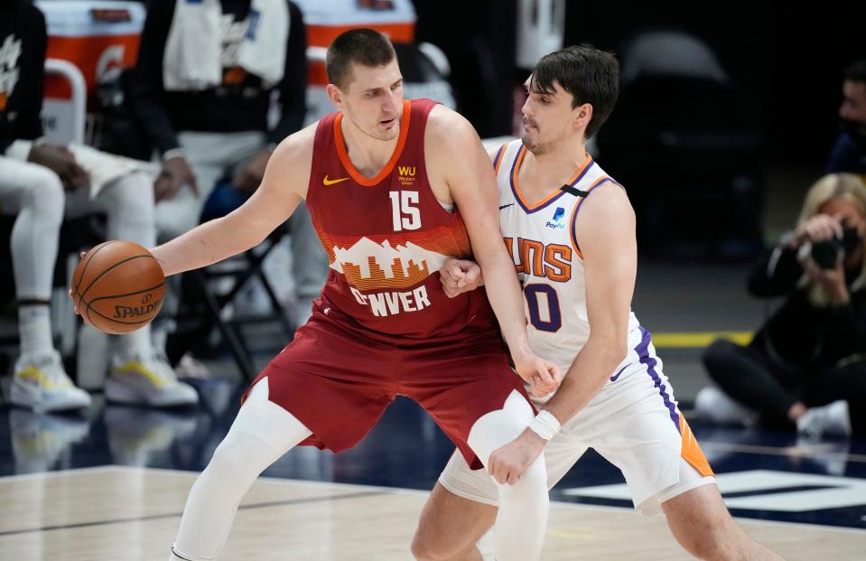 Denver Nuggets center Nikola Jokic, left, moves the ball inside as Phoenix Suns forward Dario Saric defends in the first half of Game 4 of an NBA second-round playoff series Sunday, June 13, 2021, in Denver.