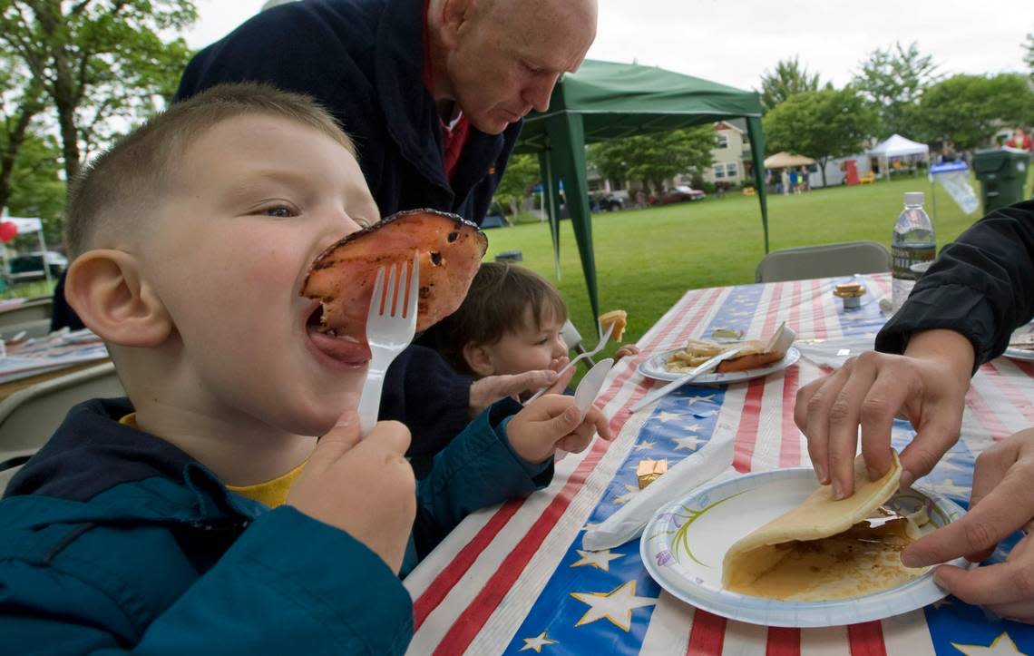 A boy takes a bite of Canadian bacon at the Independence Day pancake breakfast in DuPont, Washington, July 4, 2010