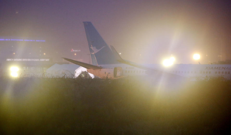 A Boeing passenger plane from China, a Xiamen Air, lies on the grassy portion of the runway of the Ninoy Aquino International Airport after it skidded off the runway while landing Friday, Aug. 17, 2018, in suburban Pasay city southeast of Manila, Philippines. All the passengers and crew of Xiamen Air flight MF8667 were safe and were taken to an airport terminal, where they were given blankets and food before being taken to a hotel. (AP Photo/Bullit Marquez)