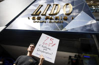 A Lido cabaret employee holds a placard reading "75 years of history may disappear" during a demonstration to try to save their jobs and the history of the cabaret, known for its dinner theater and its "Bluebell Girls" revue, Saturday, May 28, 2022 in Paris. Amid financial troubles and changing times, the venue's new corporate owner is ditching most of the Lido's staff and its high-kicking, high-glamour dance shows — which date back decades and inspired copycats from Las Vegas to Beirut — in favor of more modest musical revues. (AP Photo/Thomas Padilla)