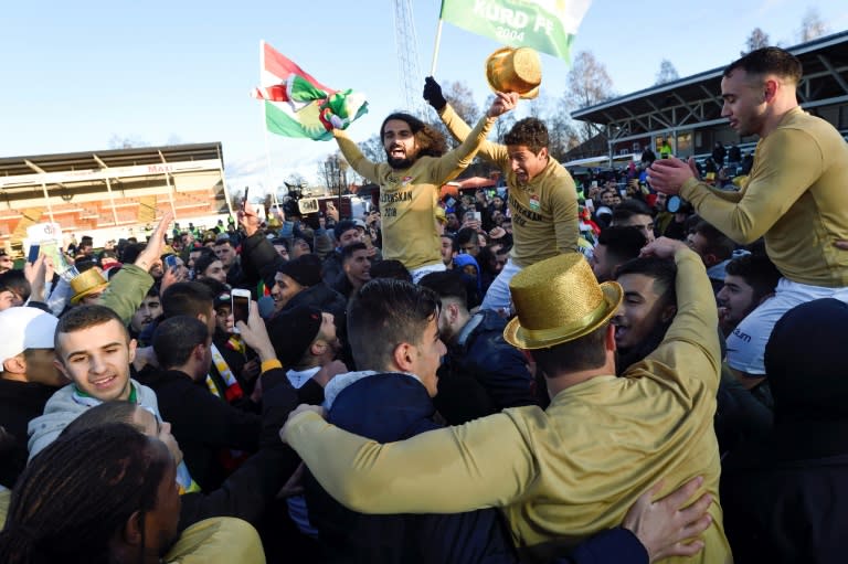 Supporters and players of Dalkurd FF, the Swedish football team founded by Kurdish immigrants, celebrate on the pitch after defeating Gothenburg's GAIS in a Superettan (Swedish second division) match and winning promotion to the top division