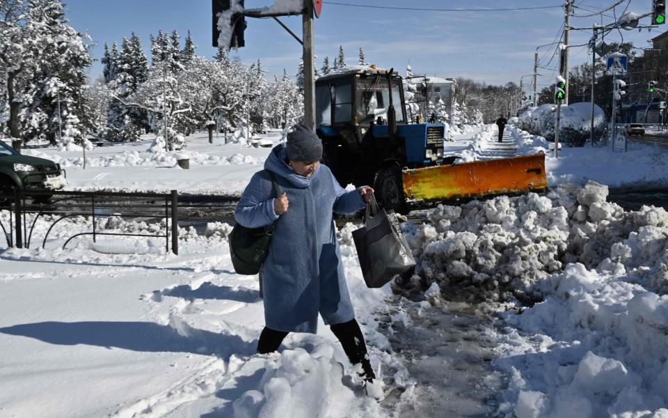 A resident walks along a snow-covered street after snowfall in Kramatorsk, Donetsk region - GENYA SAVILOV/AFP