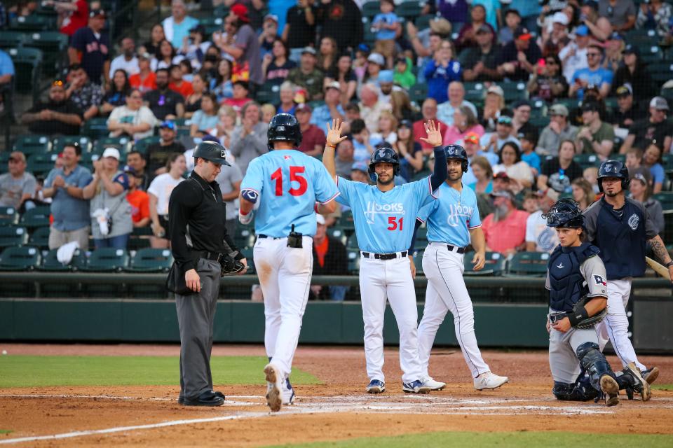 Cesar Salazar (51) and Ross Adolph (r) wait at home plate for Grae Kessinger (15) after his home run in the Corpus Christi Hooks season opener against the San Antonio Missions on April 8, 2022 in Corpus Christi, Texas.