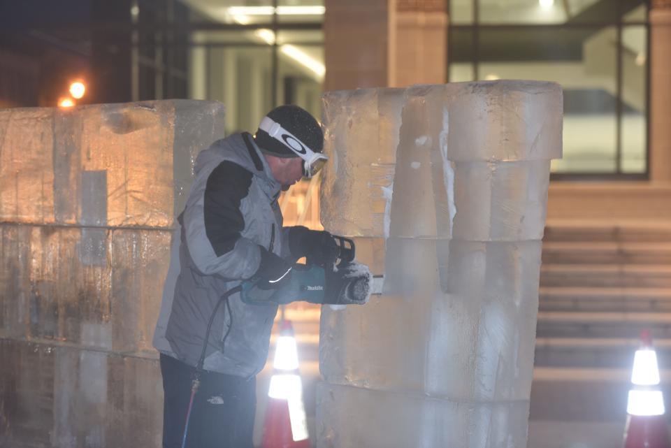 An ice carver from DiMartino Ice Company carves a giant ice sculpture  in Courthouse Plaza on the first night of IceFest 2023 in downtown Chambersburg.